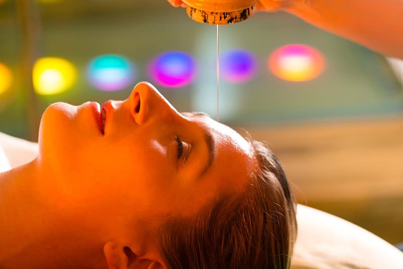 Woman enjoying a Ayurveda oil massage treatment in a spa with chromatherapy